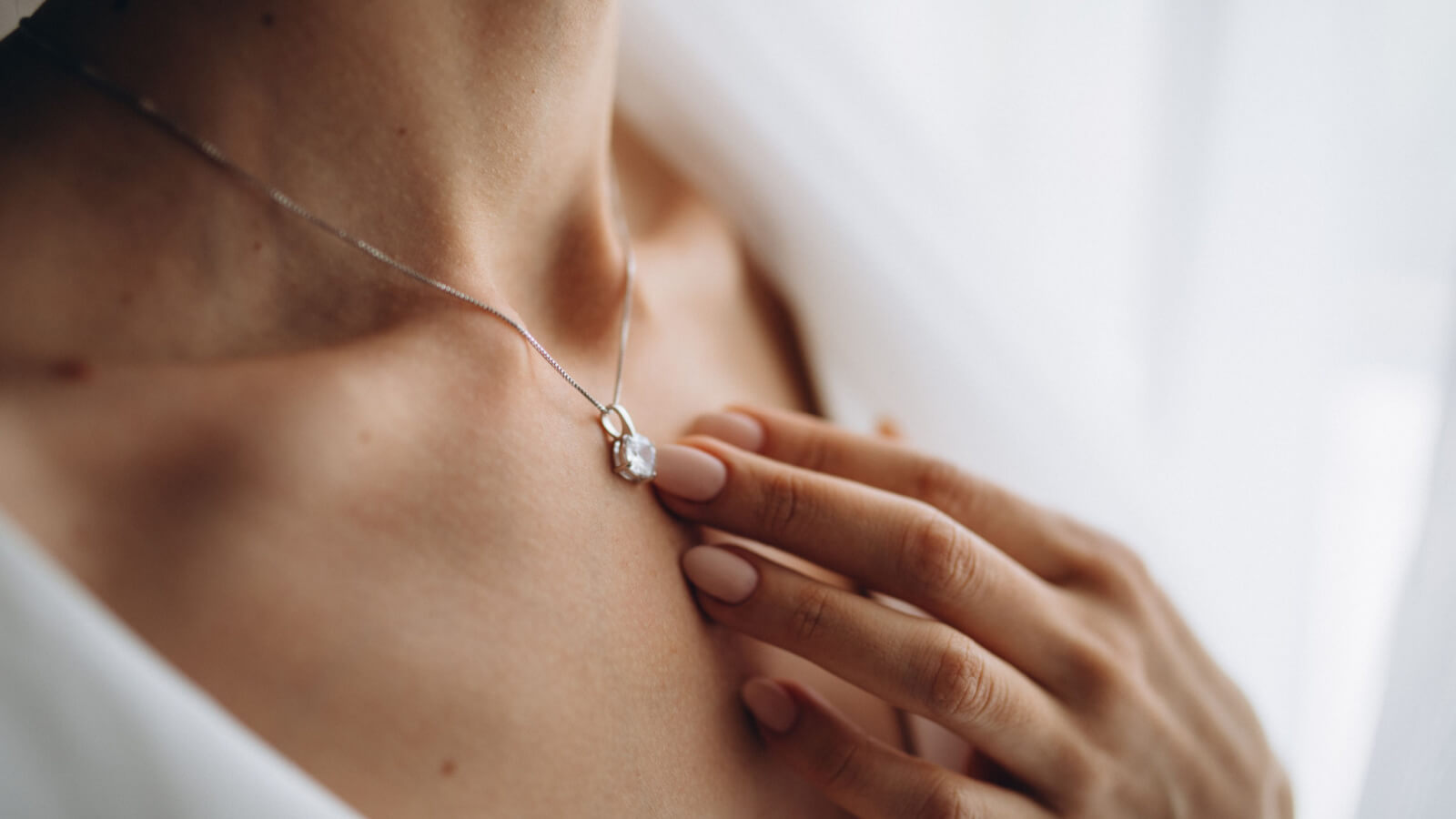 woman touching diamond pendant on neck