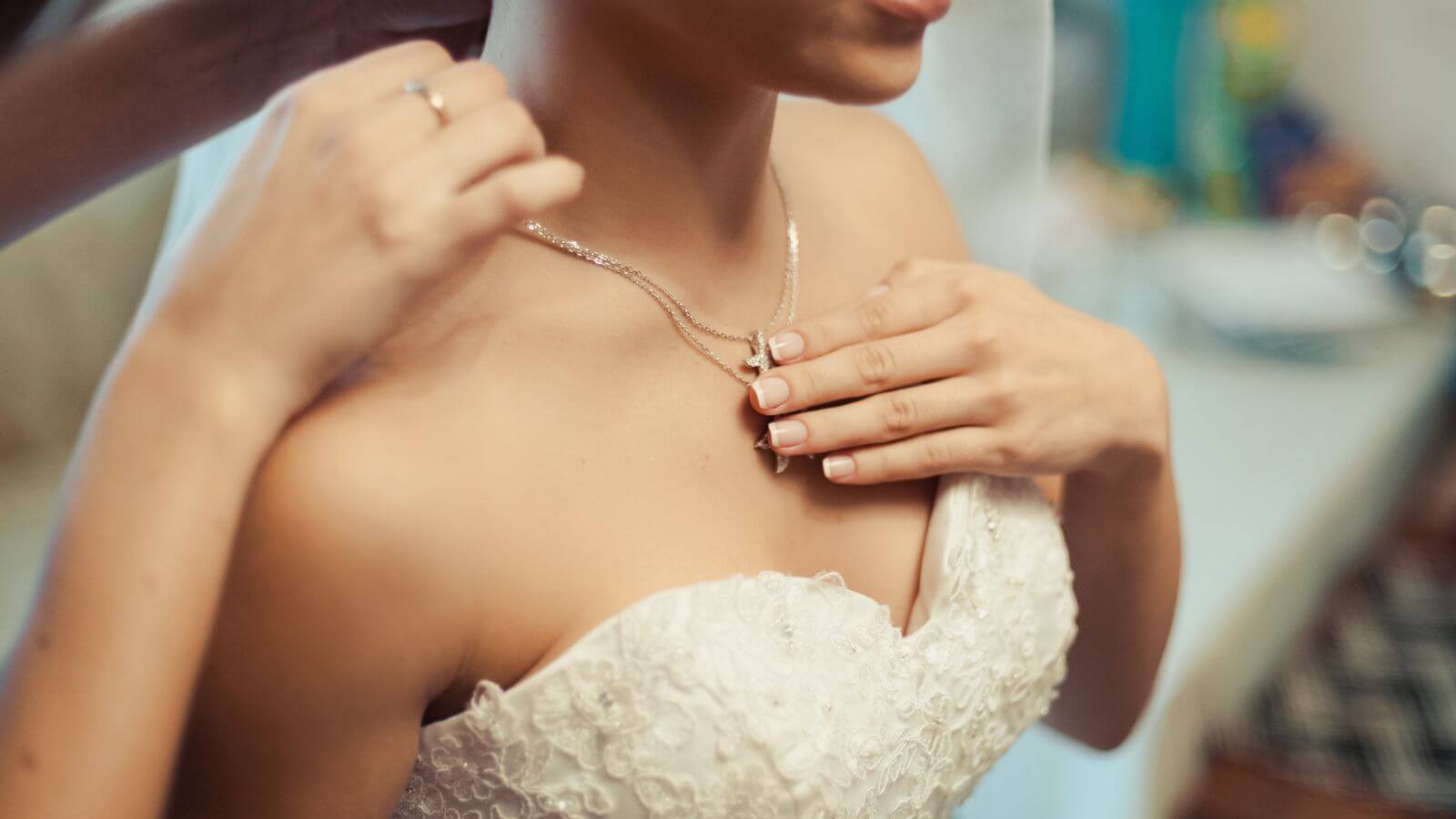 bride getting help clasping necklaces